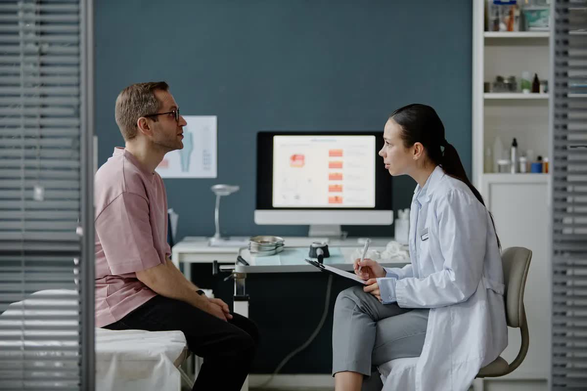 Ärztin im Gespräch mit einem Patienten im Behandlungszimmer