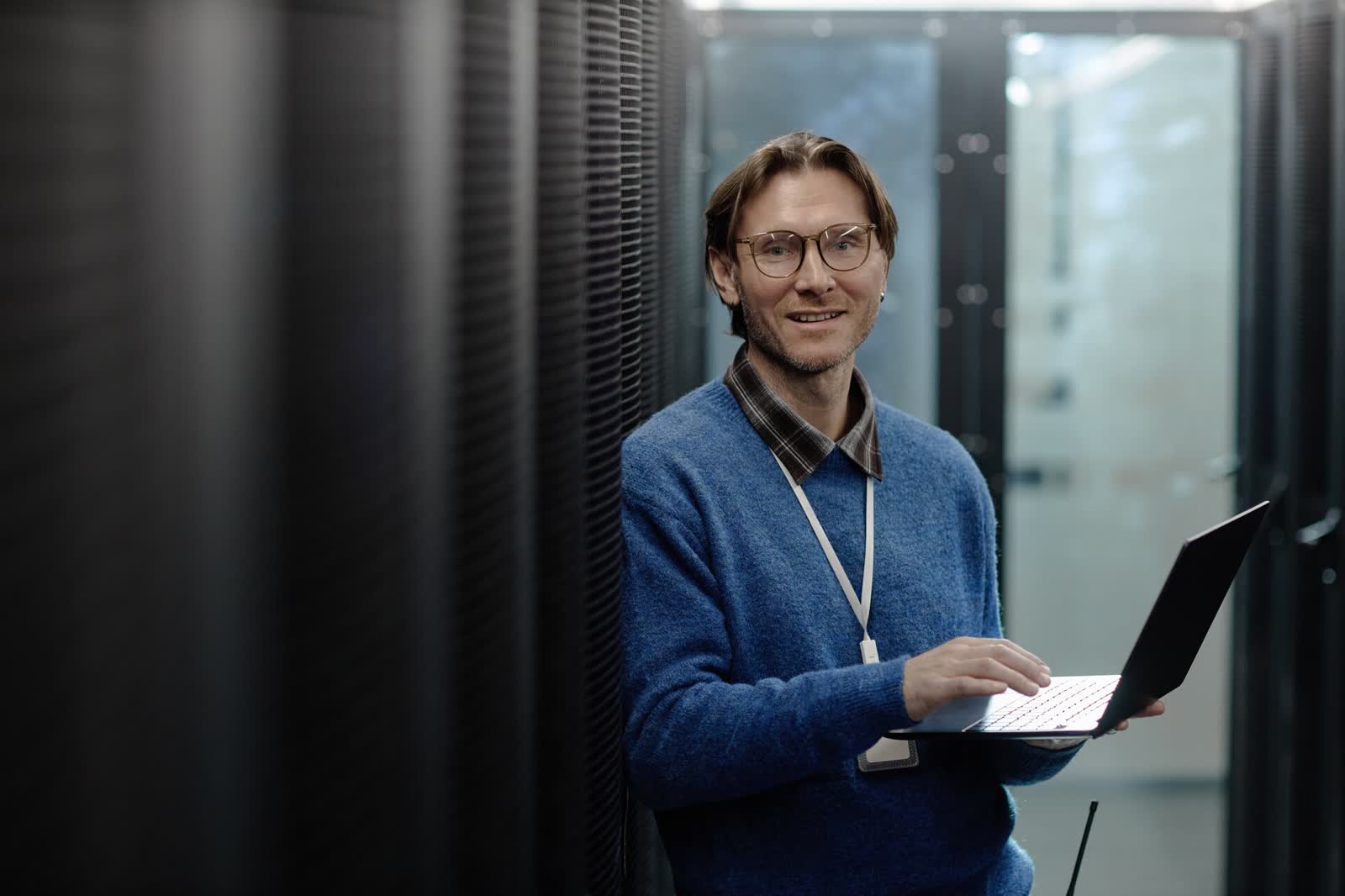 Systemadministrator mit Notebook zwischen Serverschränken