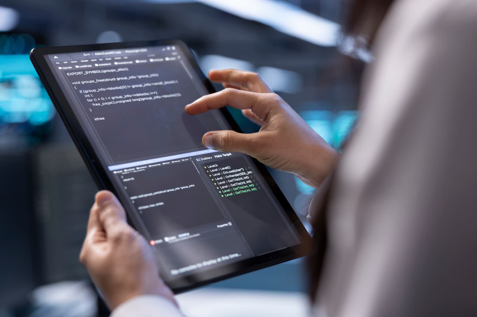 Person hält ein Tablet mit geöffnetem Programmcode